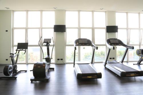 a gym with treadmills and ellipticals in a room with windows at Klima Hotel Milano Fiere in Milan
