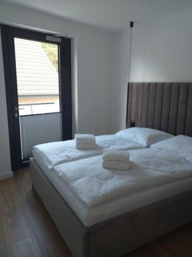 a bedroom with a large bed with two towels on it at Apartamenty Amadeus Mare in Rowy