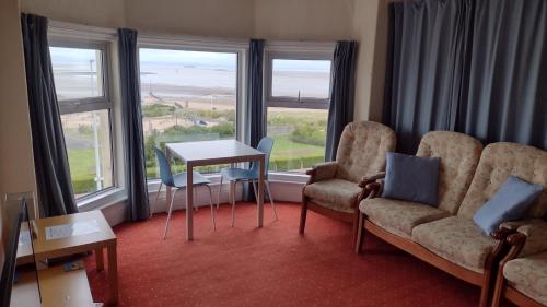 a living room with two chairs and a table and windows at The Kathrene Second Floor Sea View in Fleetwood