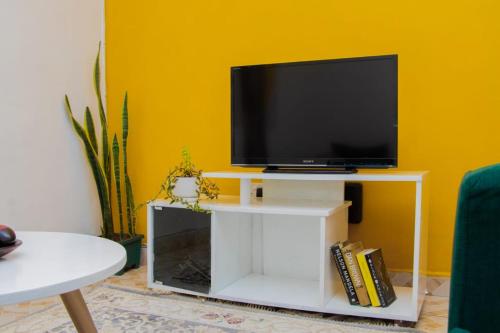 TV de pantalla plana en un soporte blanco en la sala de estar. en Cool 1 B/Room Thika Road en Nairobi