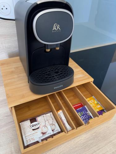 a coffee maker on a wooden table with a box at "Le Theodore" Appartement charmant proche gare avec place de parking devant, quartier très calme in Nevers