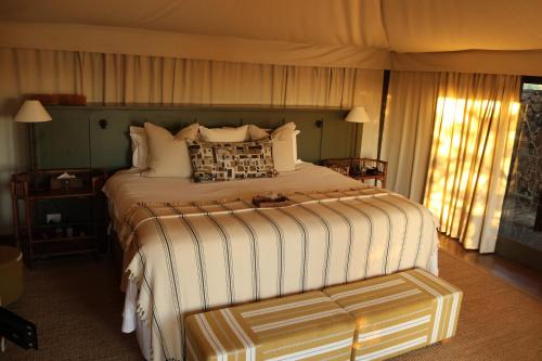 a bedroom with a large bed and a bench at Simbavati Hilltop Lodge in Timbavati Game Reserve
