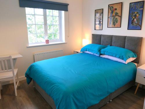 a bedroom with a bed with blue sheets and a window at Chez Ana in Saxmundham