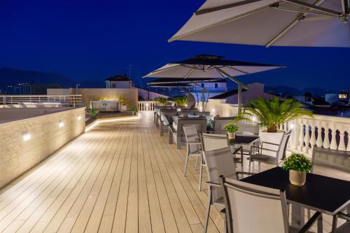 eine Terrasse mit Tischen, Stühlen und Sonnenschirmen in der Nacht in der Unterkunft Vi Suites in Viareggio