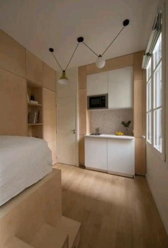 Cet appartement comprend une chambre avec un lit blanc et une cuisine. dans l'établissement Studio cosy Paris 6ème Bon Marché, à Paris