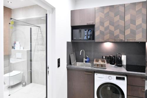 une salle de bain avec une machine à laver et un lavabo dans l'établissement Parking Gratuit À Paris Montmartre Charme et Élégance - Appartement Lumineux à Deux Pas du Sacré-Cœur - Parking Gratuit - Sacré-Cœur -Metro Anvers, à Paris