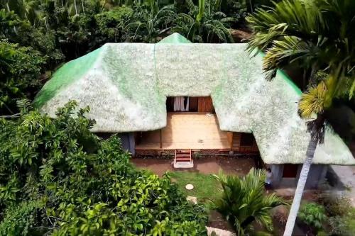 une petite maison avec un toit vert et des arbres dans l'établissement Maison en bambou, éco lodge, à Pila