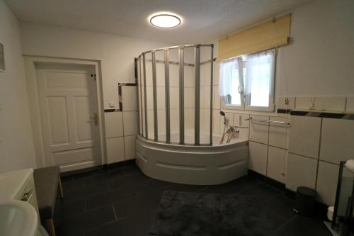 baño con bañera, lavabo y ventana en Ferienhaus Alte Wagnerei Steinatal - Ühlingen-Birkendorf, en Ühlingen-Birkendorf