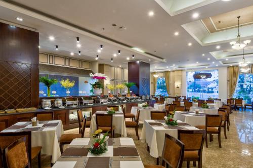 um restaurante com mesas e cadeiras brancas e um bar em La Sapinette Hotel Dalat em Da Lat