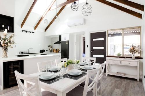 a kitchen and dining room with a white table and chairs at Salt & Pepper; Beautiful Town House in Margs! in Margaret River Town