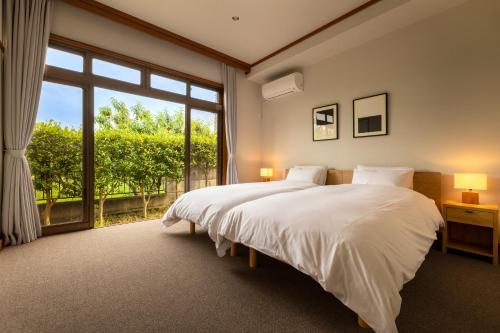 a bedroom with a bed and a large window at Temple Hotel 南アルプス法源寺 in Minami Alps