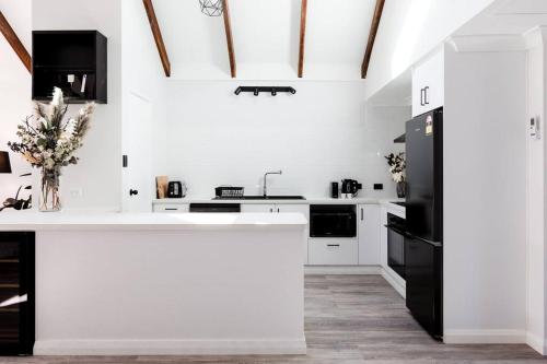 a kitchen with white counters and a black refrigerator at Salt & Pepper; Beautiful Town House in Margs! in Margaret River Town