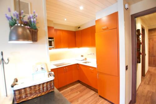 eine Küche mit orangefarbenen Schränken und einem Waschbecken in der Unterkunft Apartamento con jardín - Montana Park in Enveitg