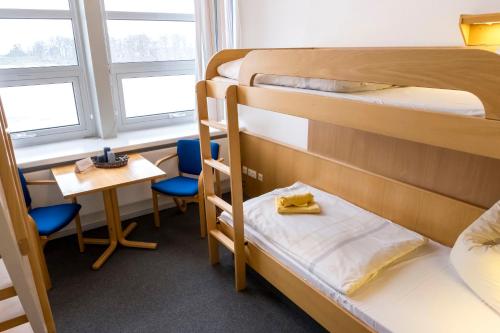 a room with two bunk beds and a table and chairs at Jugendherberge Lauenburg Zündholzfabrik in Lauenburg