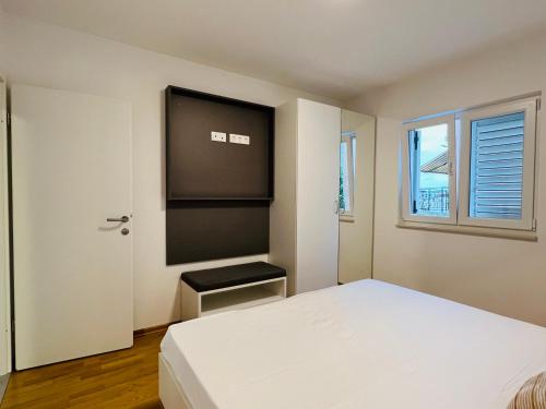 a bedroom with a white bed and a window at Apartmani AViS in Selce