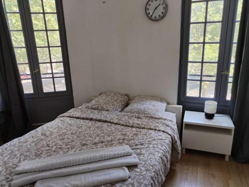 a bedroom with a bed with pillows and a clock on the wall at Studio Saint-Jacques in Paris
