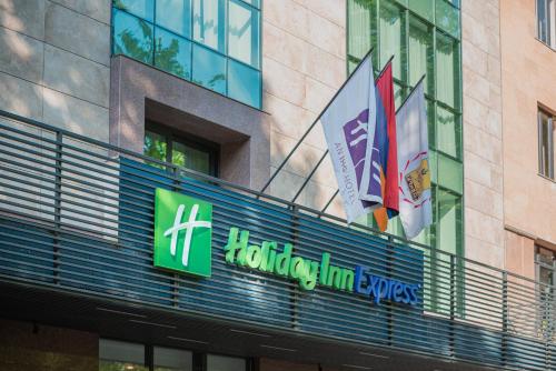 Una señal para un edificio con banderas. en Holiday Inn Express - Yerevan, an IHG Hotel, en Ereván