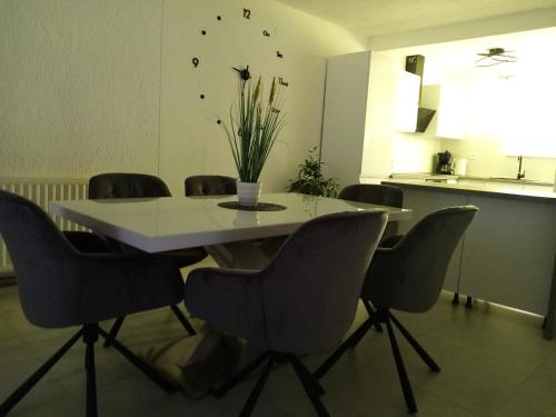 a dining room table with chairs and a vase on it at Natalija apartmani in Sveti Juraj