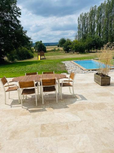 - une table et des chaises en bois à côté de la piscine dans l'établissement Logement B / Clos des Saunières, à Bligny-lès-Beaune