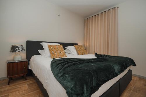 a bedroom with a large bed with a green blanket at Villa Yvonne in Ostend