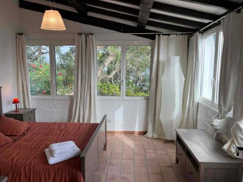 a bedroom with a red bed and two windows at Villa Ormarine, vue exceptionnelle sur la baie de Cannes et le Mercantour in Les Adrets de l'Esterel
