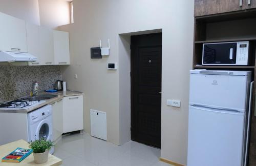 eine Küche mit einem weißen Kühlschrank und einer Mikrowelle in der Unterkunft Old City Apartment in Baku