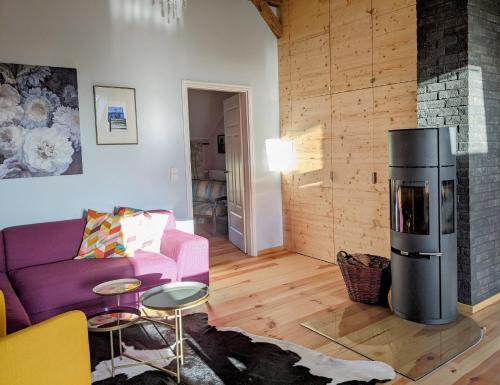 a living room with a purple couch and a fireplace at Ferienloft Himmelblau im 1870 Uckermark in Kröchlendorf