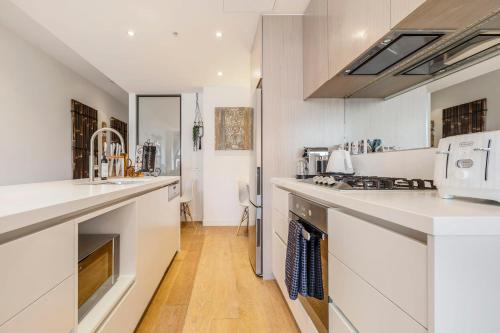 - une cuisine avec des comptoirs blancs et un évier dans l'établissement Charming 1-Bedroom Heritage Apartment, à Melbourne