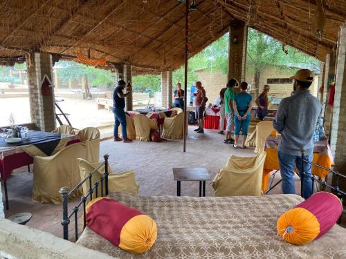 a group of people standing at tables in a tent at Umaid Desert Camp, Raisar in Bikaner