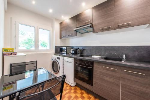 La cuisine est équipée de placards en bois, d'un évier et d'un lave-vaisselle. dans l'établissement Cannes Branly :2BDR Apartment, à Cannes