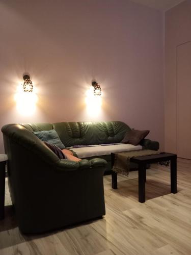 sala de estar con sofá verde y mesa en Saules Apartament en Daugavpils