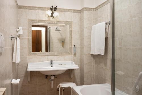 a white bathroom with a sink and a mirror at Hotel San Marco in Gubbio