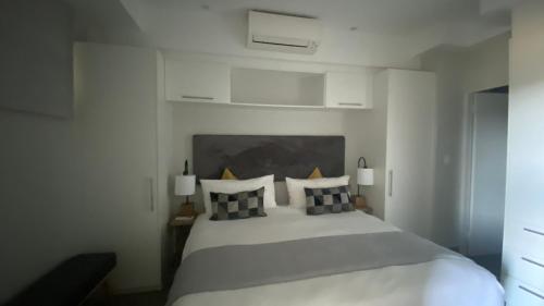 ein Schlafzimmer mit einem weißen Bett mit schwarzen und weißen Kissen in der Unterkunft Luxurious Resorts in Pretoria