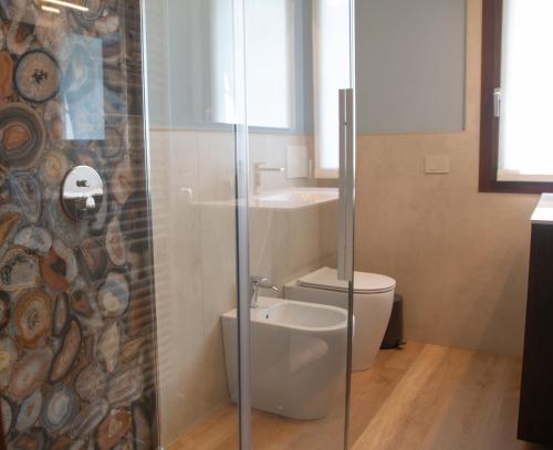 a bathroom with a toilet and a glass shower at Casa Hemingway - WelcHome in Stresa