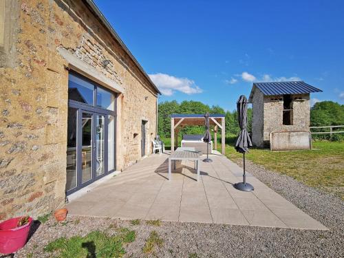a patio with a chair and an umbrella next to a building at A l'Orée du Lac, 500m lac de Chamboux in Saint-Martin-de-la-Mer