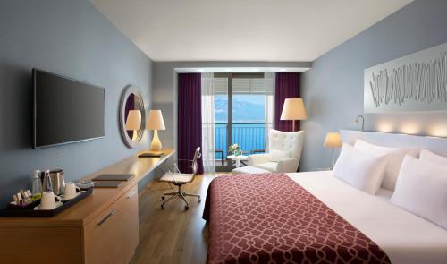 Habitación de hotel con cama, escritorio y TV. en Akra Antalya en Antalya