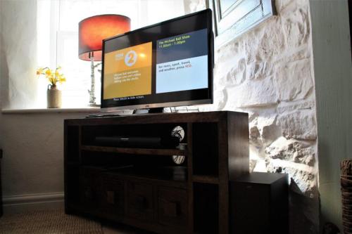 a flat screen tv sitting on a wooden entertainment center at The Roost - Askrigg 18th Century Cottage in Askrigg