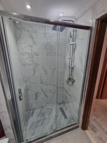 La salle de bains est pourvue d'une douche avec une porte en verre. dans l'établissement Appartement de Prestige, vue Kasbah, Mer et Vieux Port, à Tanger