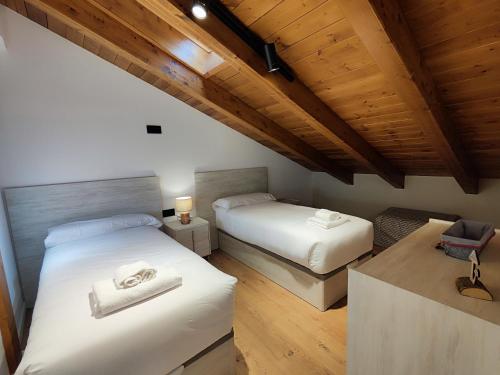 two beds in a room with wooden ceilings at Apartaments El Trèvol in Camprodon