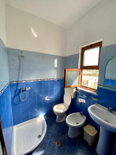 a blue and white bathroom with two toilets and a sink at Vila Rrodhe in Durrës