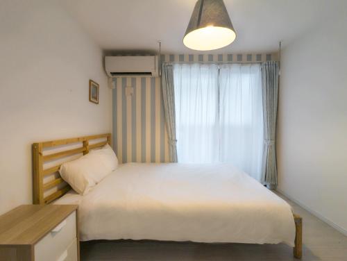 1 dormitorio con cama blanca y ventana en japan house itabashi, en Tokio