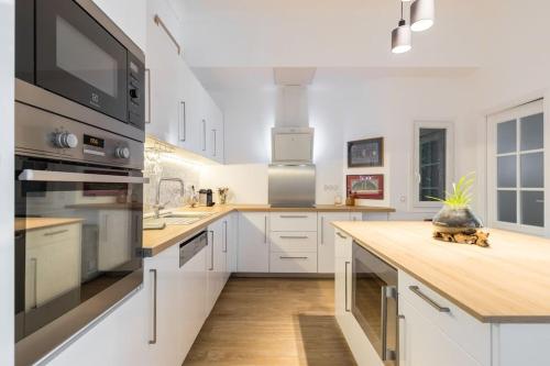 une cuisine avec des armoires blanches et un comptoir en bois dans l'établissement Large Haussmanian appartment in the heart of Nice, à Nice