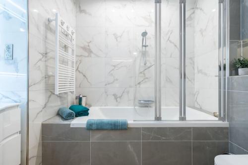 une salle de bain blanche avec une baignoire et une douche dans l'établissement Large Haussmanian appartment in the heart of Nice, à Nice