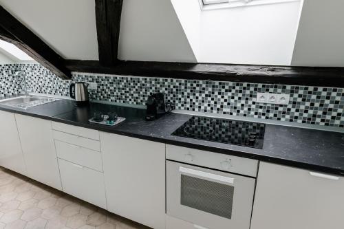 a kitchen with white cabinets and a black counter top at Rezidence U Kamenného mostu in Písek
