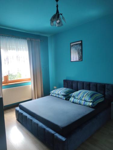 a blue bedroom with a bed with a blue wall at Alfa 2 apartament 4 in Bystra