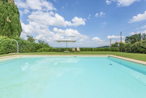 a large blue swimming pool with an umbrella at Villa Boschetto in Montepulciano