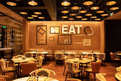 a restaurant with tables and chairs and a cat sign on the wall at Renaissance Hangzhou Northeast in Yuhang