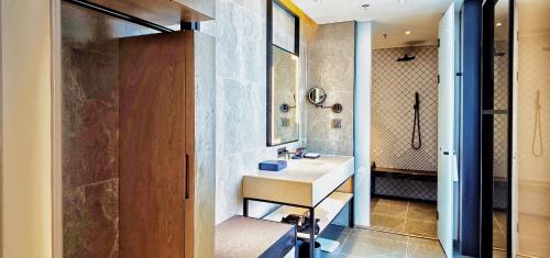 uma casa de banho com um lavatório e um chuveiro em Aloft Yantai em Yantai