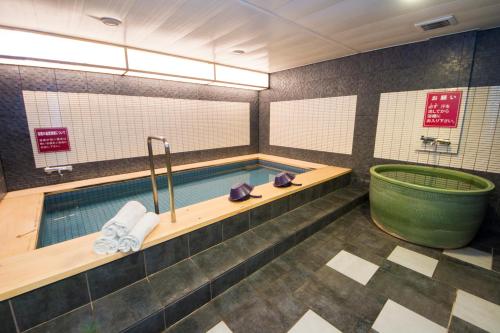 een badkamer met een zwembad en een bad bij Grand Park Hotel Panex Iwaki in Iwaki