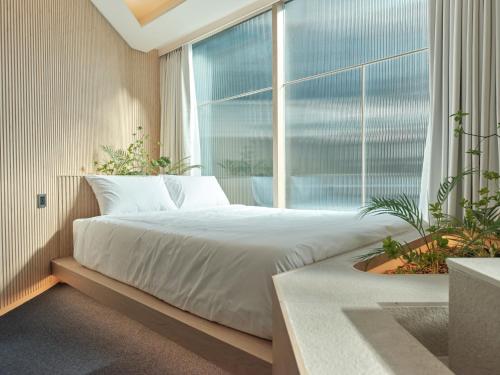 a bedroom with a bed and a large window at UH Suite Seoul Square in Seoul
